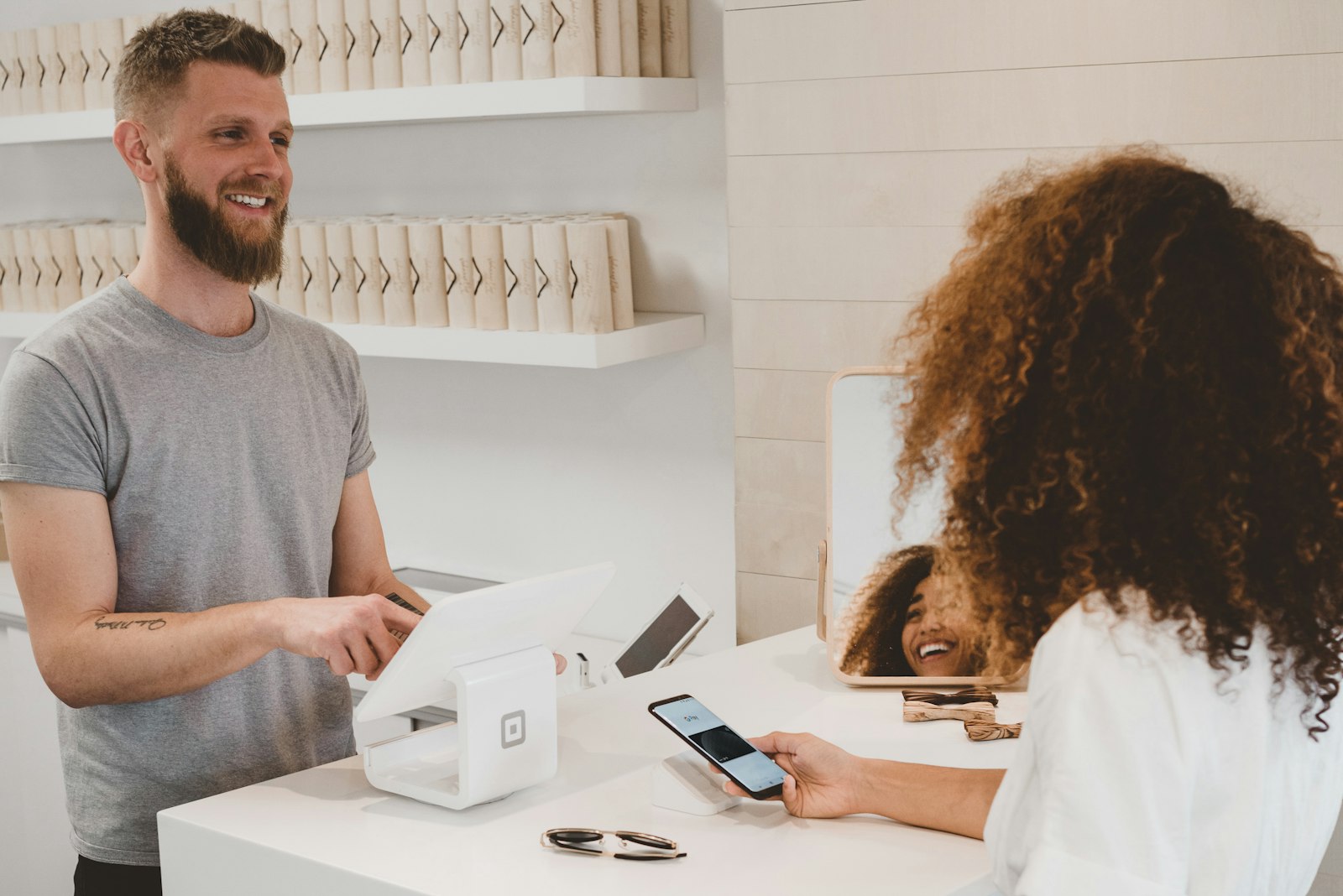 A smiling shop owner taking a mobile payment from a happy customer